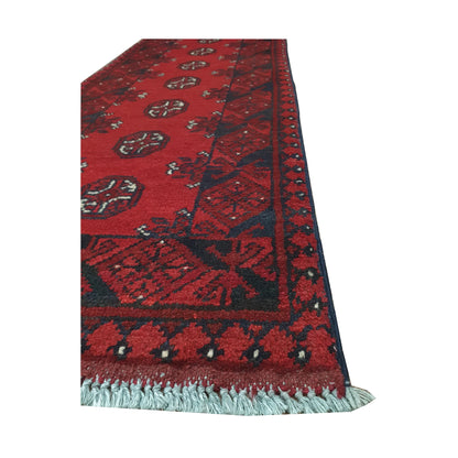 Angled border and fringe detail of Afghan Turkoman runner rug showing red wool pile, diamond side panels and tribal motifs