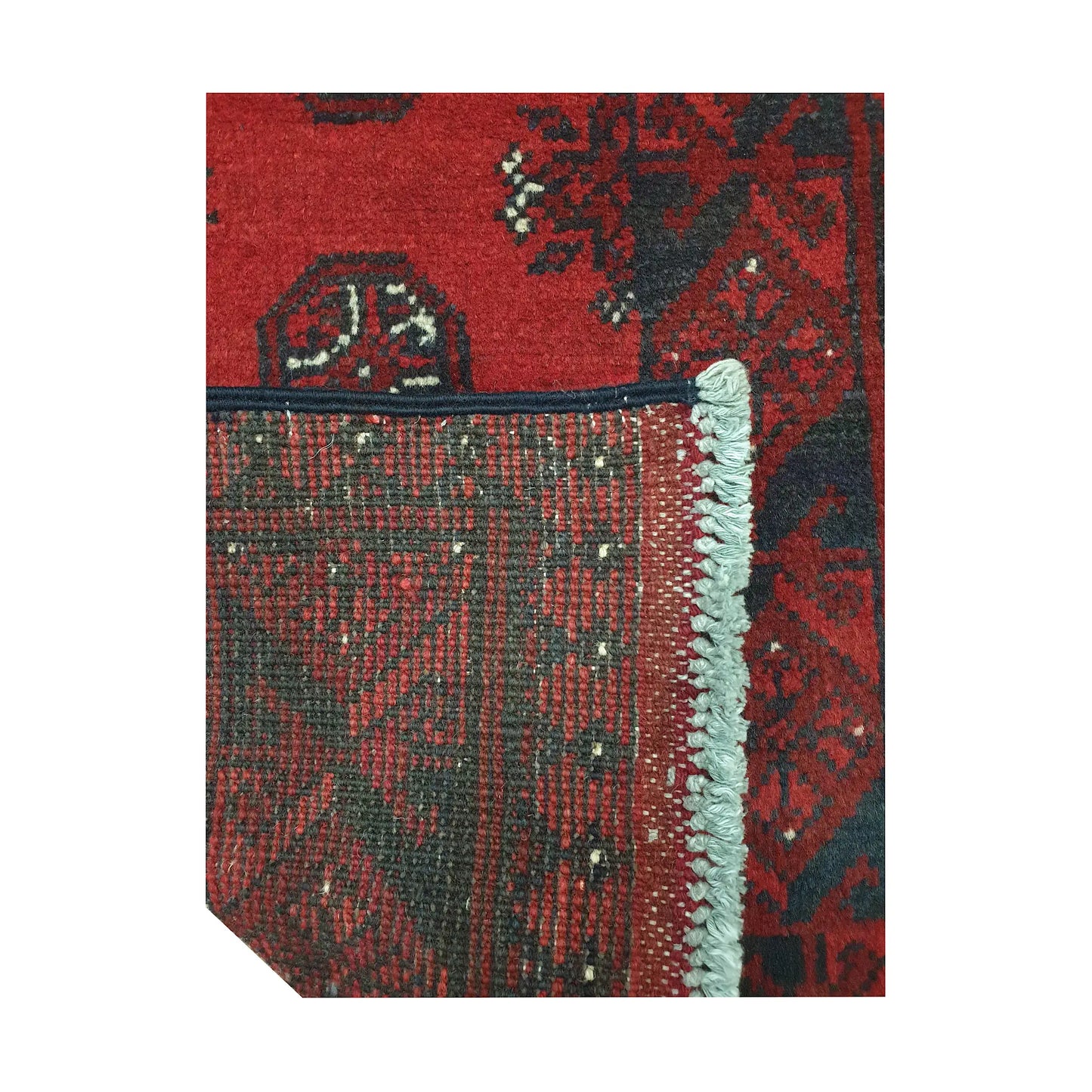 Folded corner detail of Afghan Turkoman runner rug showing the back of the rug, fringe and red front pattern