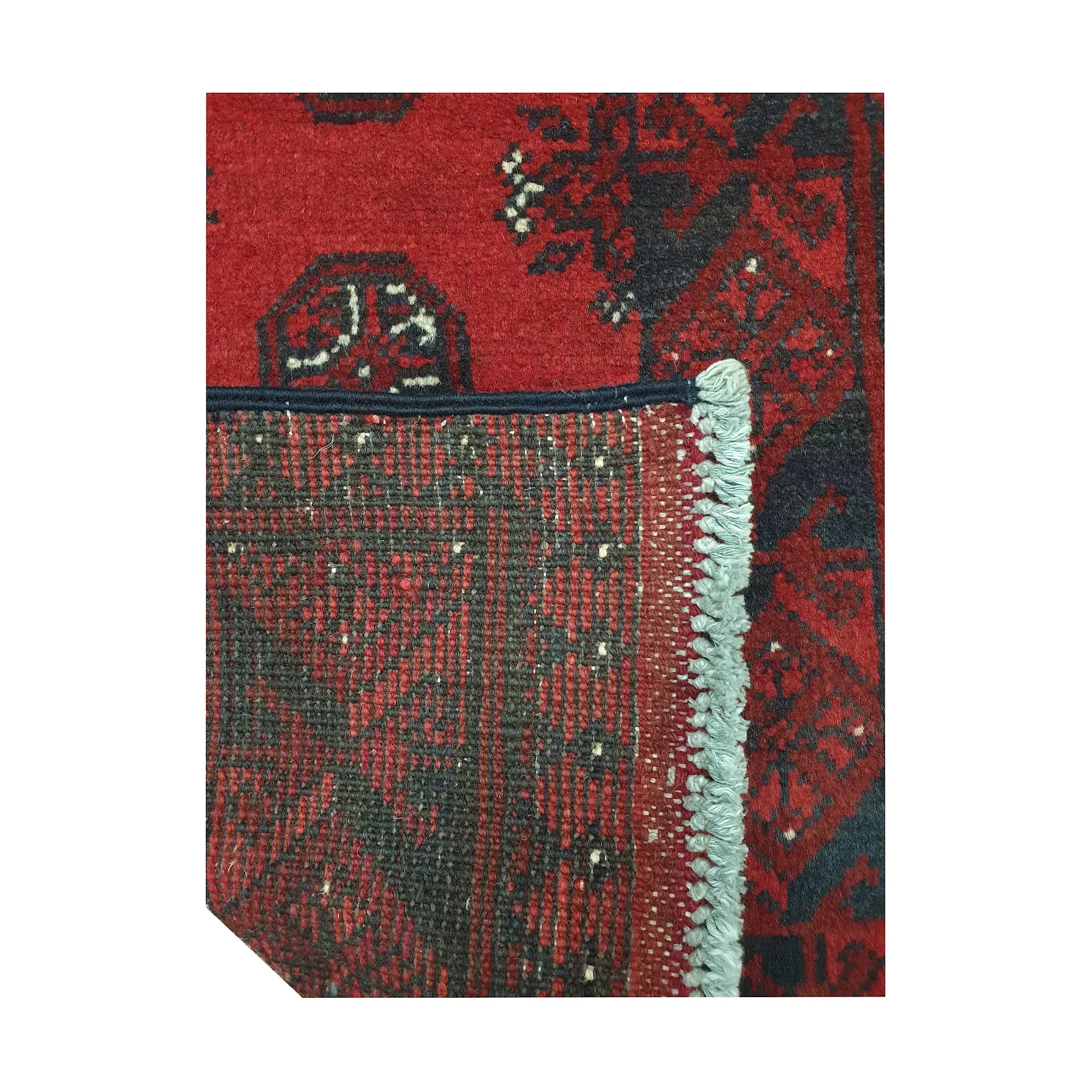 Folded corner detail of Afghan Turkoman runner rug showing the back of the rug, fringe and red front pattern