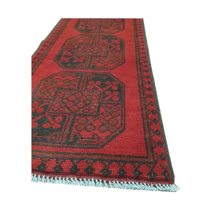Angled border and fringe detail of Afghan Turkoman runner rug showing red wool pile, charcoal edging and tribal motifs