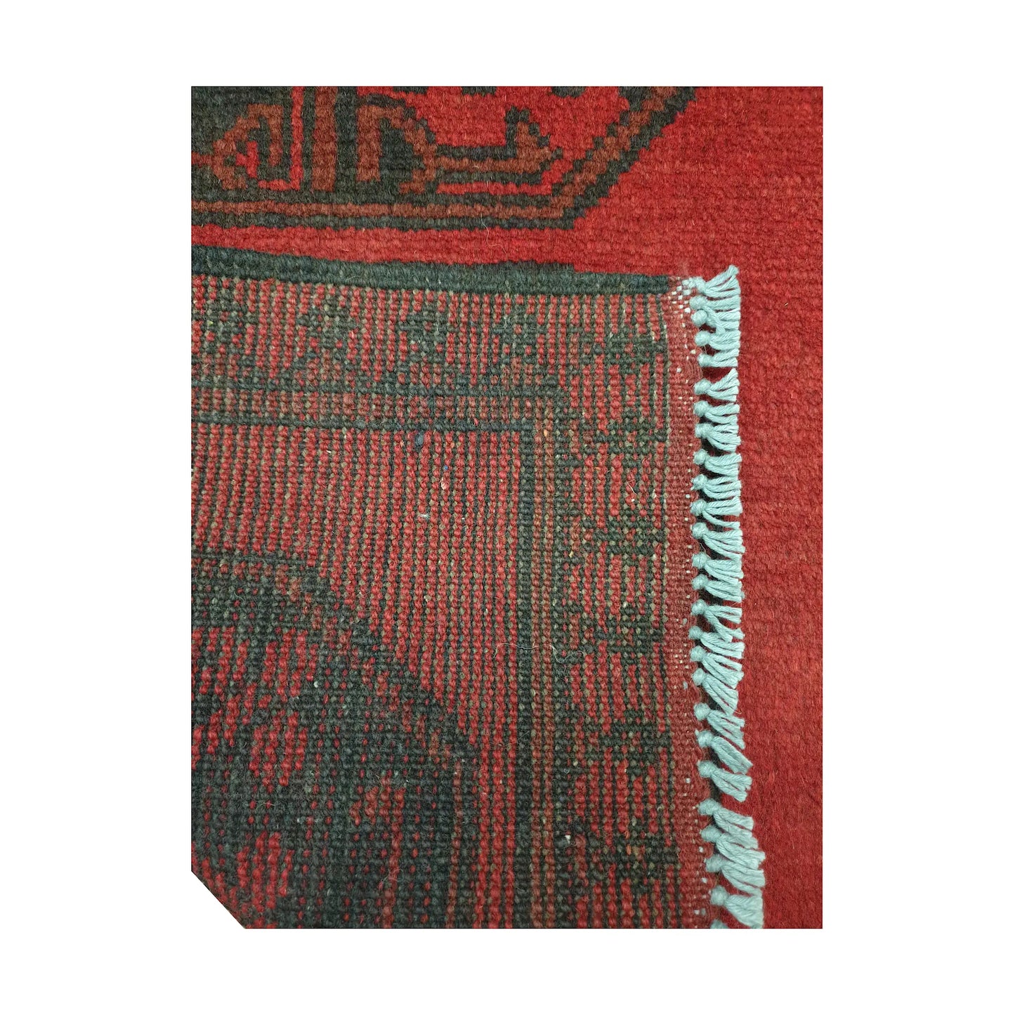 Folded corner detail of Afghan Turkoman runner rug showing the back of the rug, fringe and red front pattern