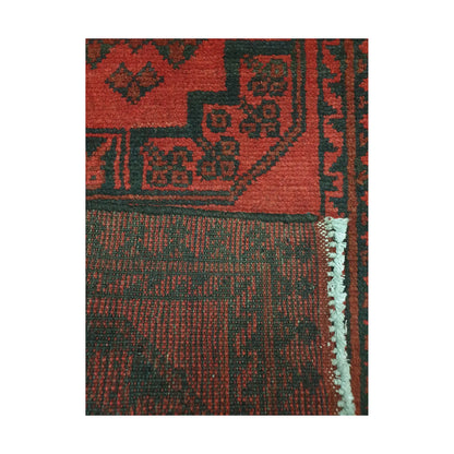 Folded corner detail of Afghan Turkoman runner rug showing the back of the rug, fringe and red front pattern