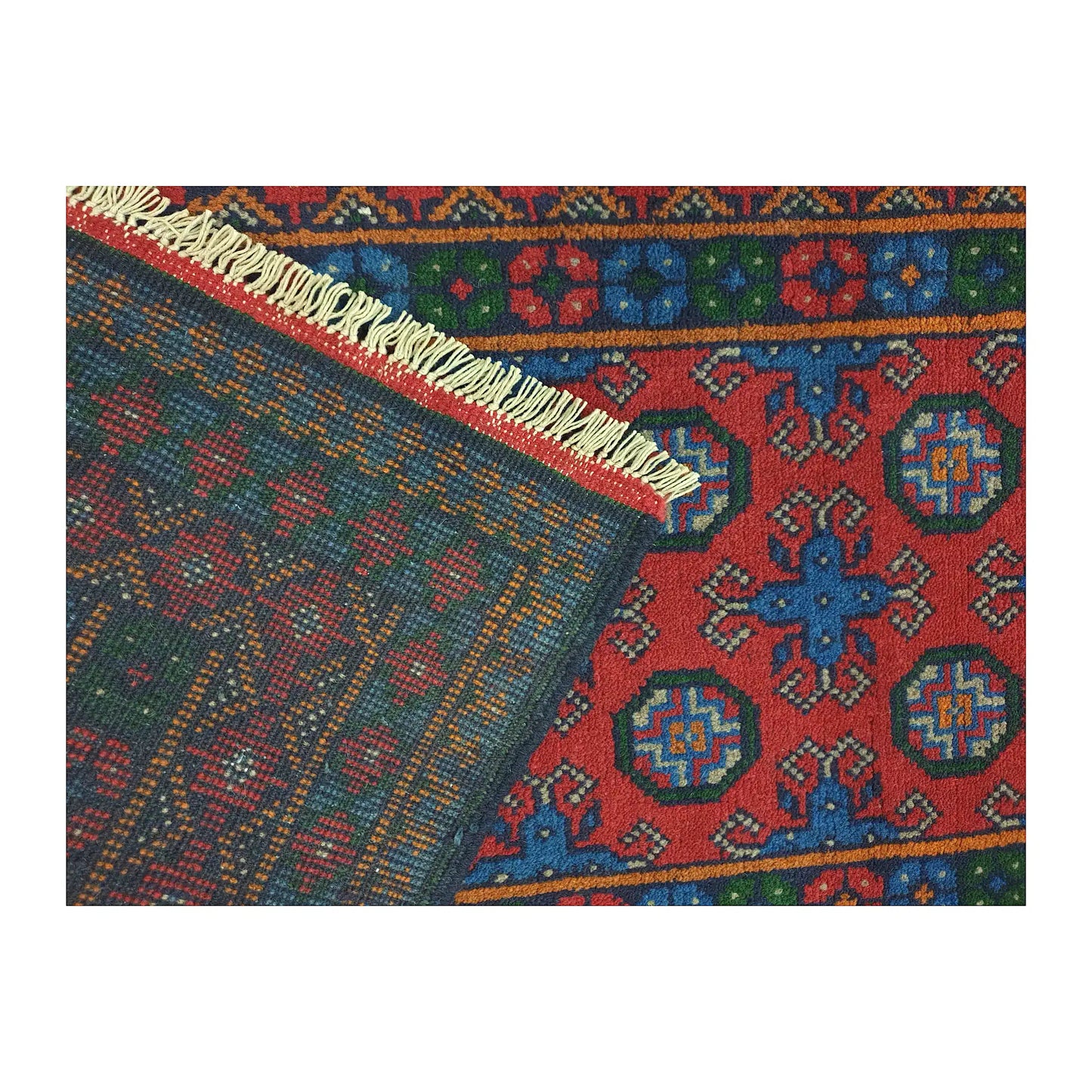 Folded corner showing the patterned front, reverse weave and cream fringe of the Turkoman runner
