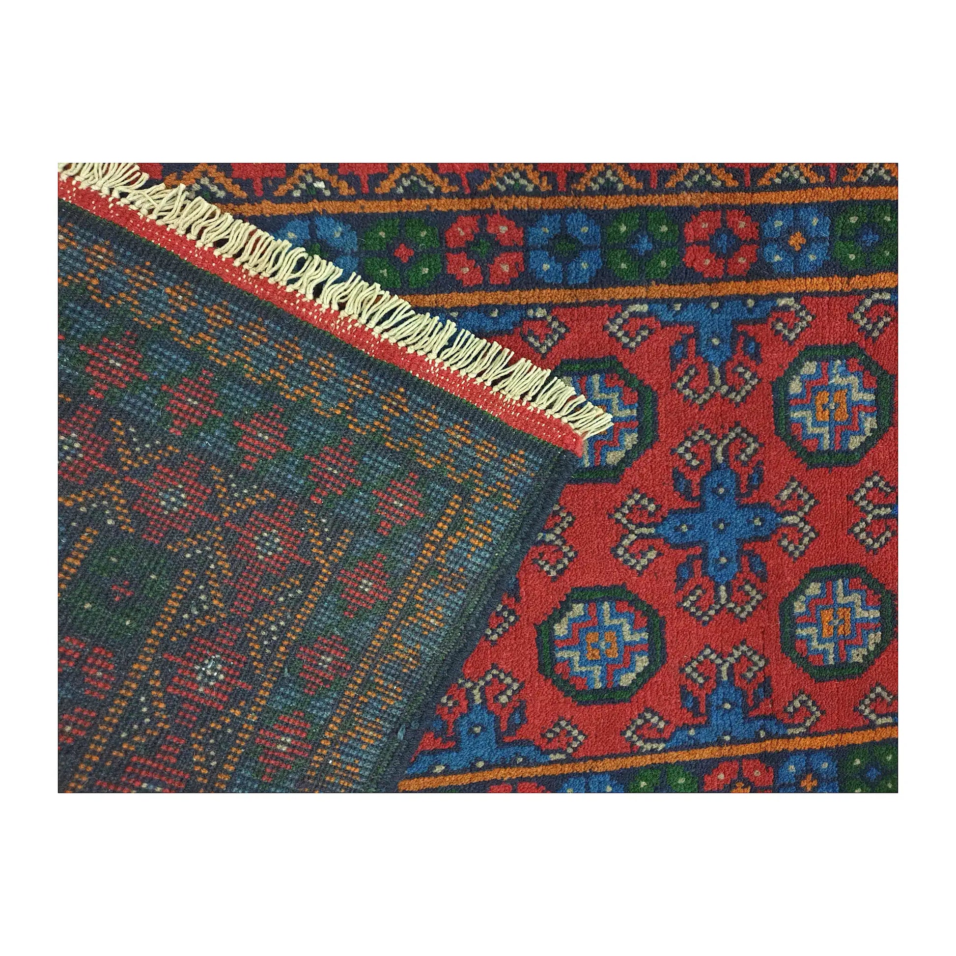 Folded corner showing the patterned front, reverse weave and cream fringe of the Turkoman runner