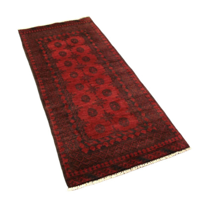 Angled view of Afghan Turkoman wool rug with dark geometric borders, 197 x 92 cm