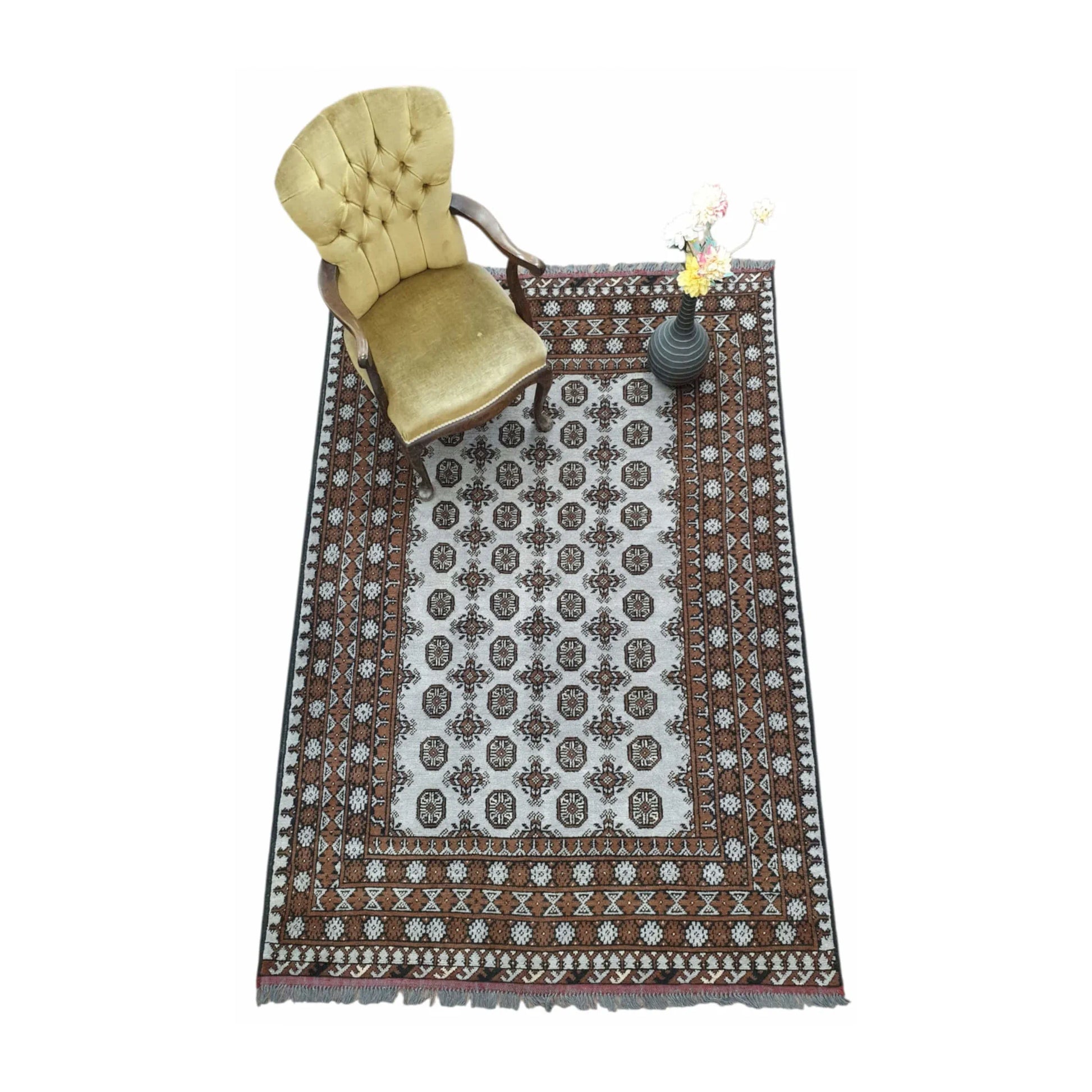 Styled angled view of Afghan Turkoman wool rug with decorative objects showing the repeating gul pattern and warm brown border