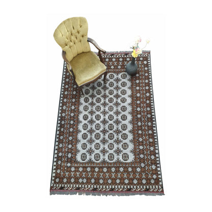 Styled angled view of Afghan Turkoman wool rug with decorative objects showing the repeating gul pattern and warm brown border