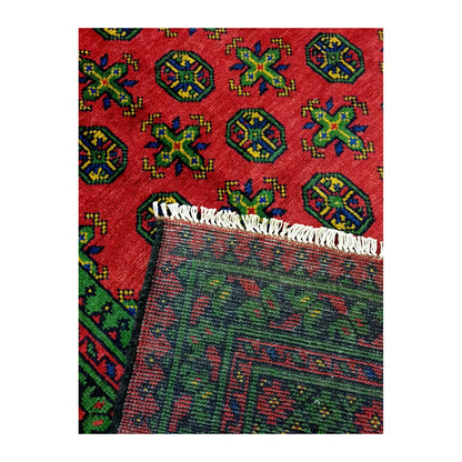 Folded corner of Afghan Turkoman rug showing the patterned face, reverse weave and ivory fringe