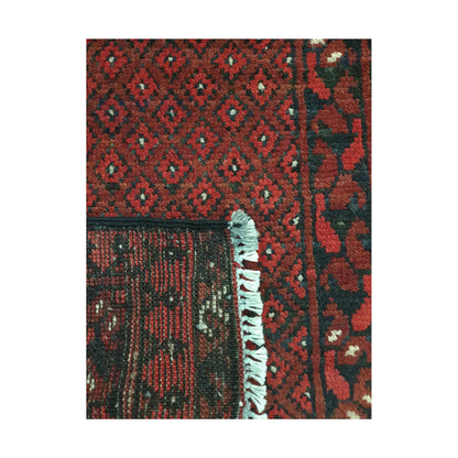 Folded corner detail of Afghan Turkoman wool rug showing the back, fringe and red patterned surface