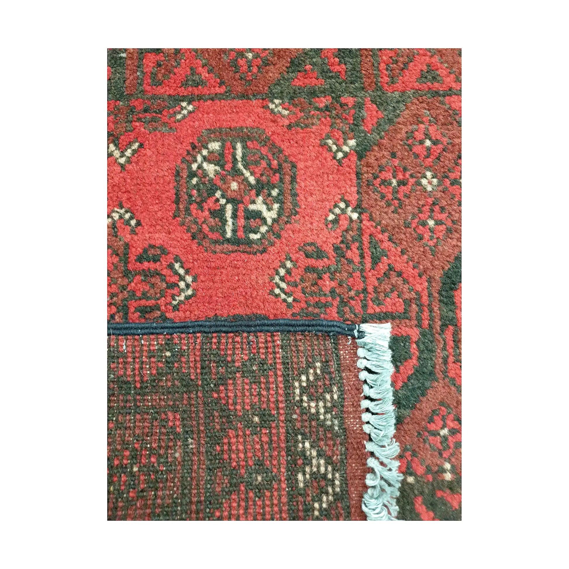 Folded corner back detail of Afghan Turkoman wool rug showing weave structure and red patterned surface