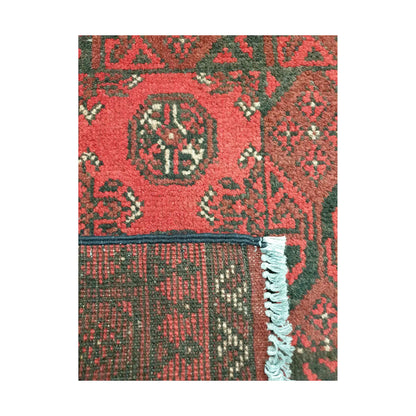 Folded corner back detail of Afghan Turkoman wool rug showing weave structure and red patterned surface
