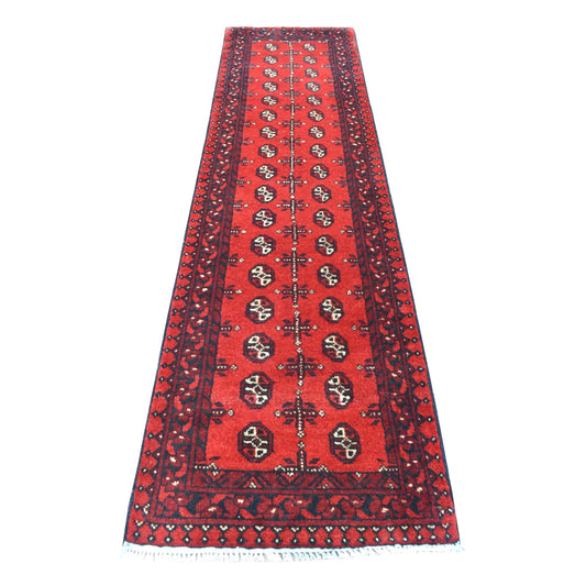 Full view of Afghan Turkoman hand-knotted wool runner with deep red field, repeating oval guls and dark geometric borders, 236 x 64 cm