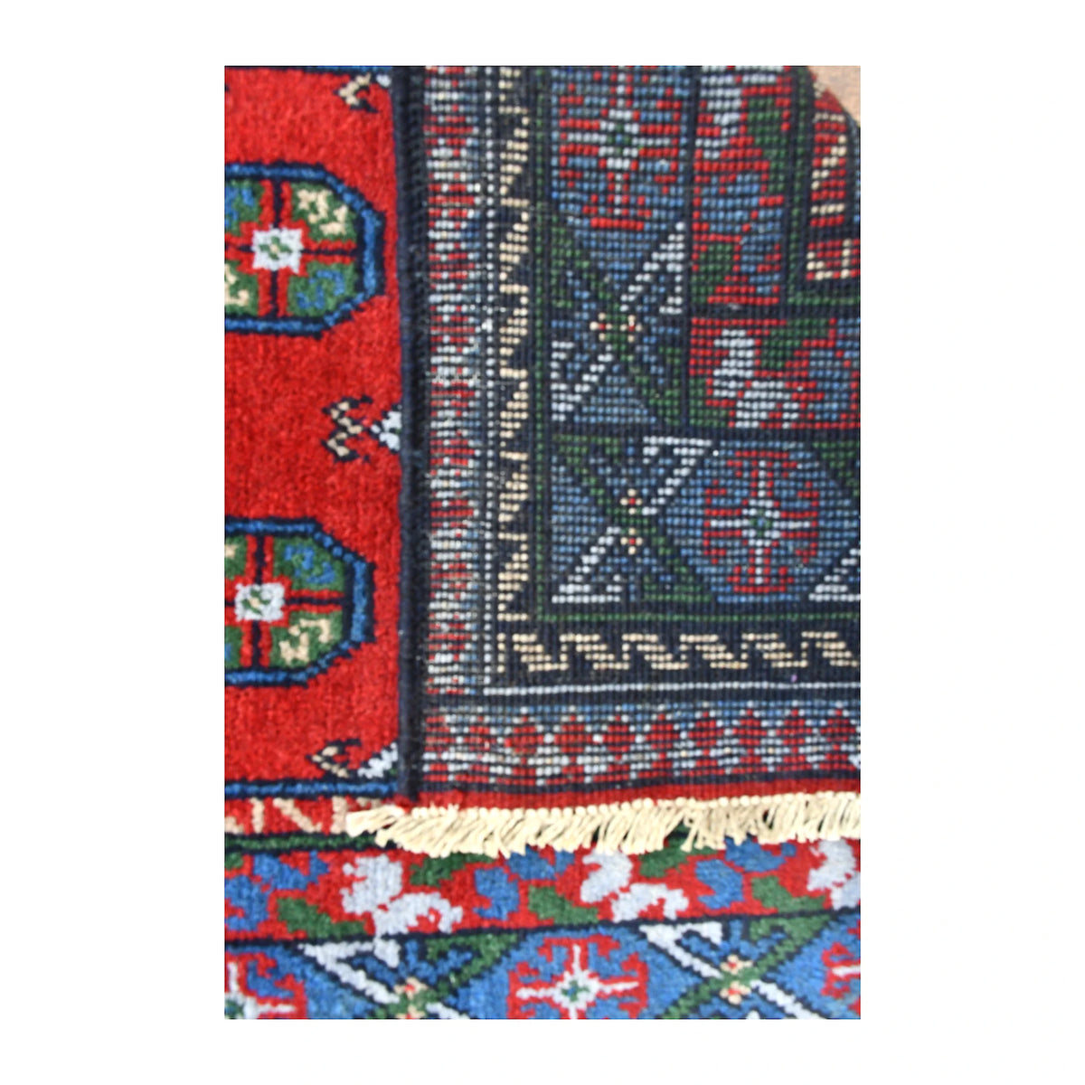 Folded-corner detail of Afghan Turkoman runner showing the reverse weave beside its red field and deep blue and purple borders
