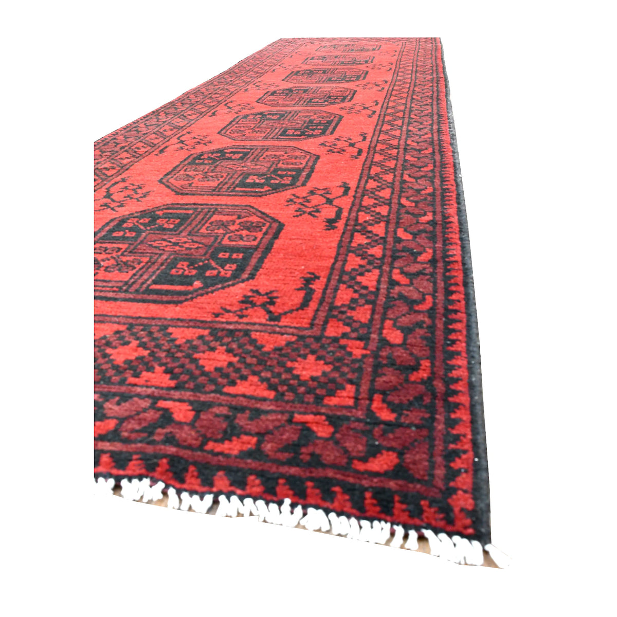 Angled view of Afghan Turkoman runner showing its widely spaced octagonal guls, dark layered borders and ivory fringe