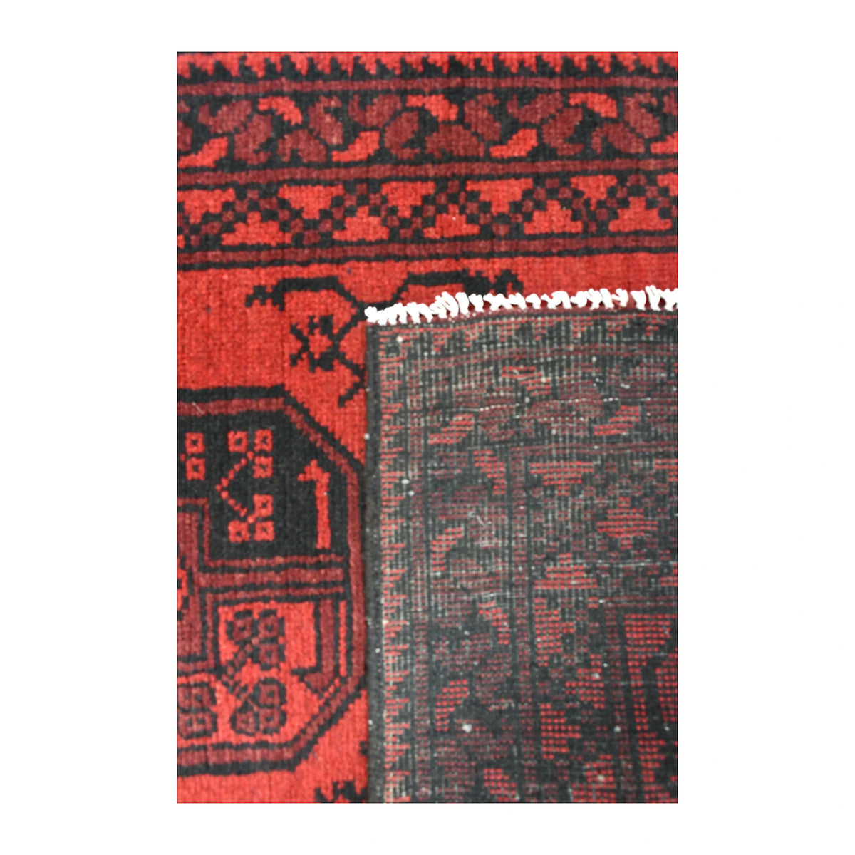 Folded-corner detail of Afghan Turkoman runner showing the reverse weave beside its red gul field and dark geometric border