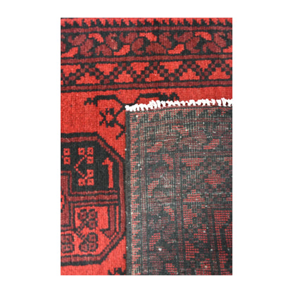 Folded-corner detail of Afghan Turkoman runner showing the reverse weave beside its red gul field and dark geometric border