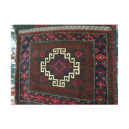 Close-up of Afghan wool saddle bag pile face with an ivory hooked medallion and deep red geometric border