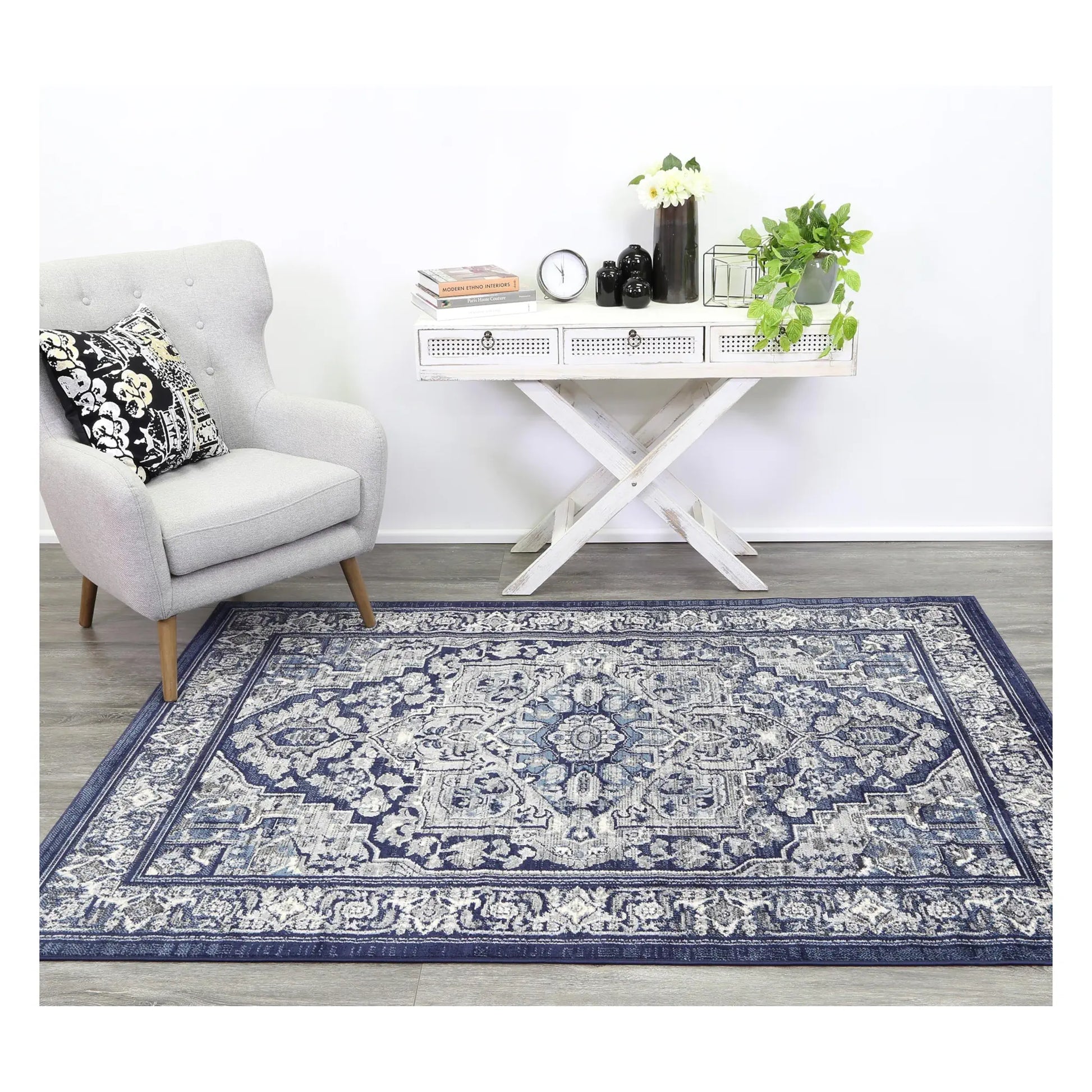 Arya navy rosette traditional rug styled with white furniture in a neutral setting