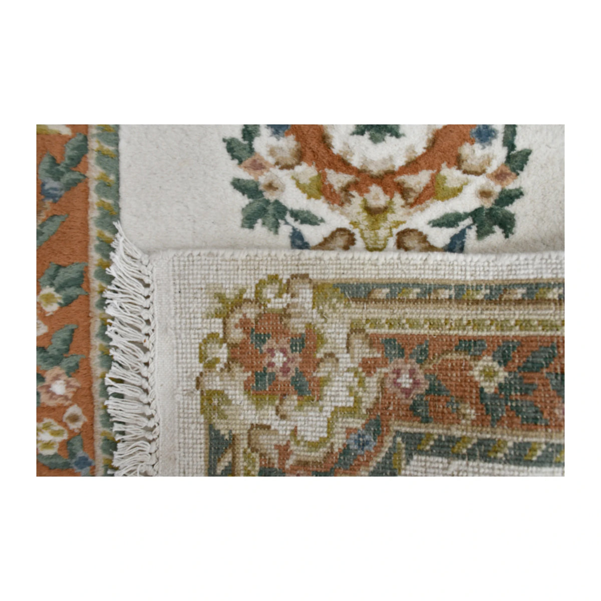 Folded-corner detail of Aubusson rug showing the reverse weave, floral front and pale fringe