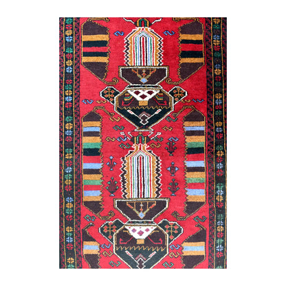 Field detail of Baluchi rug showing two angular medallions, multicoloured striped panels and small motifs across the red ground