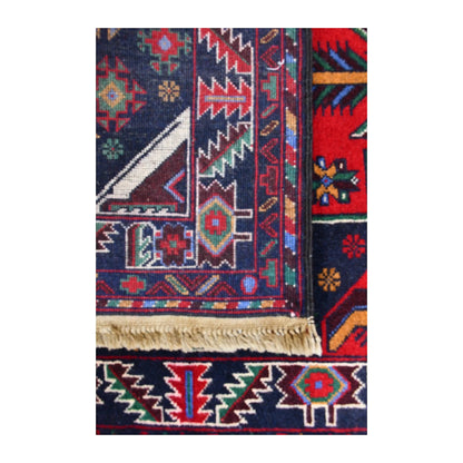 Folded corner of Baluchi runner showing the patterned face, reverse weave and fringed finishing edge