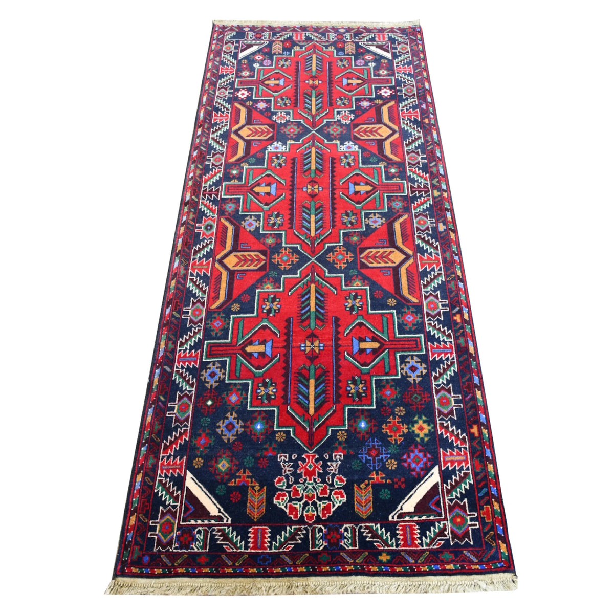 Full view of Baluchi hand-knotted runner rug with bold red geometric medallions on a deep navy field, 200 x 83 cm