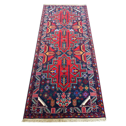 Full view of Baluchi hand-knotted runner rug with bold red geometric medallions on a deep navy field, 200 x 83 cm