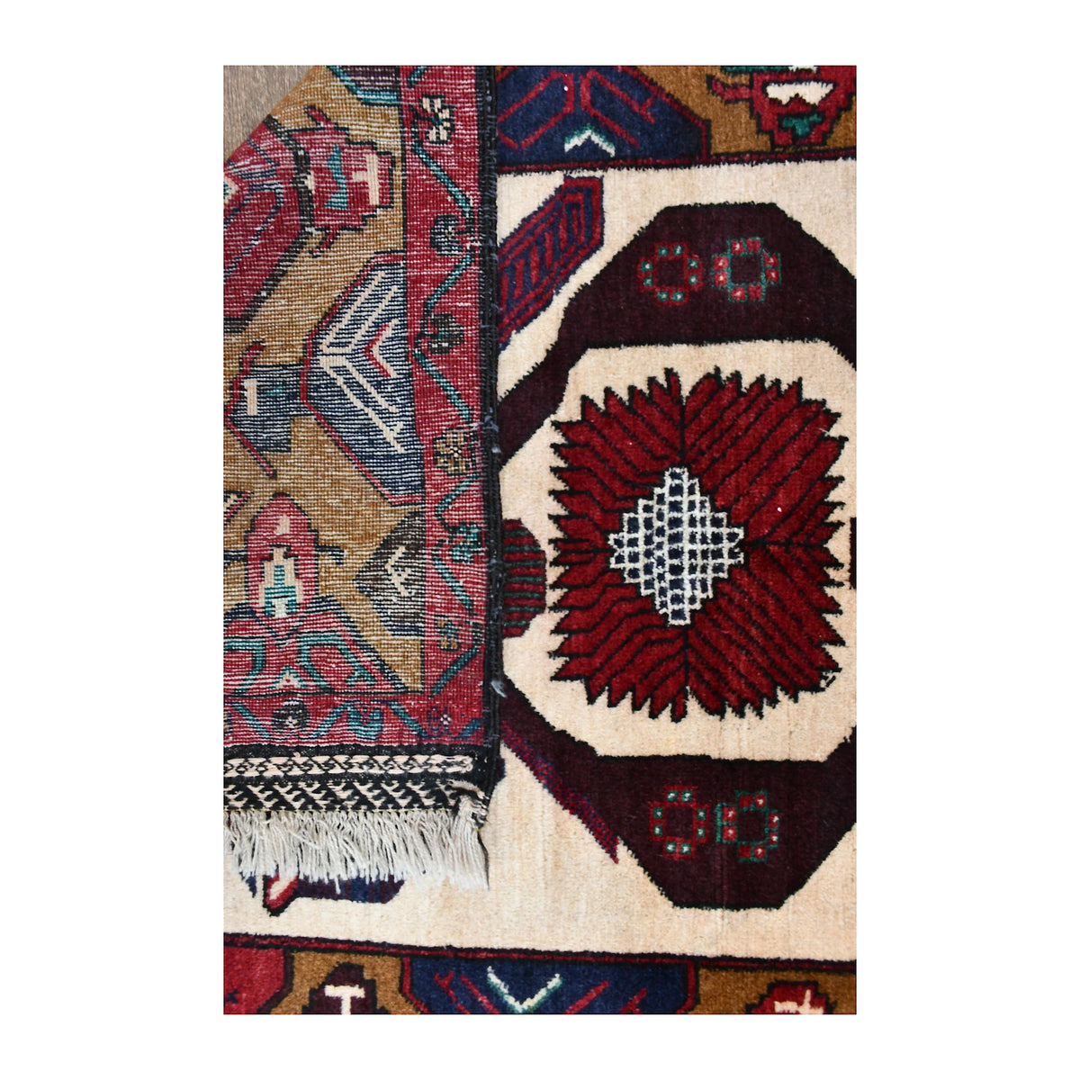 Folded-corner detail of Baluchi rug showing the front pattern, reverse weave and finished edge