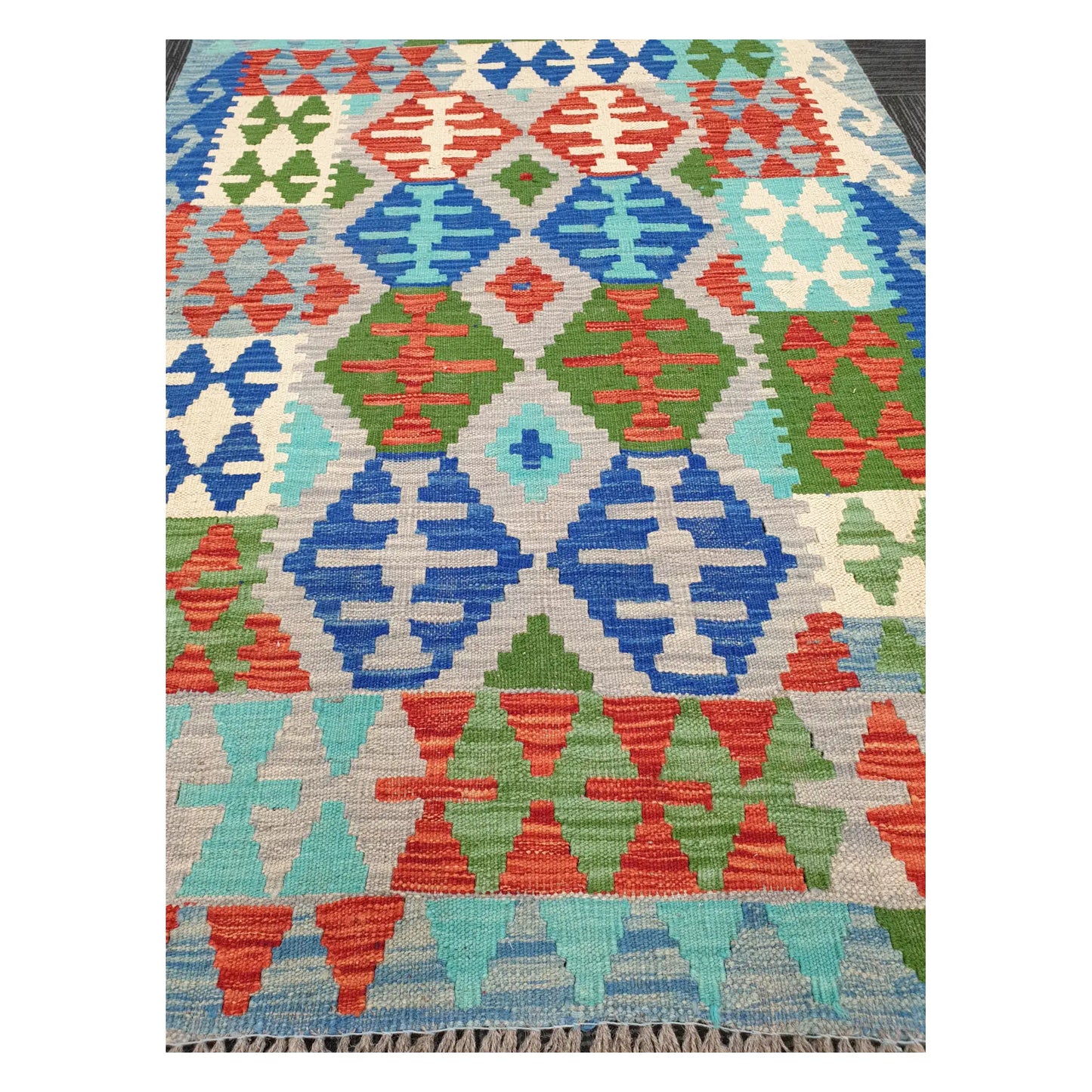 Close-up of Chobi Kilim rug with blue diamond motifs, coral accents, and green tribal detailing, 144 x 105 cm