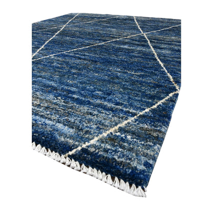 Angled view of blue Moroccan rug showing cobalt, denim and navy pile, raised ivory lines and pale fringe