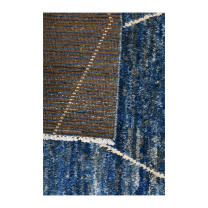 Folded-corner detail of Moroccan rug showing the reverse weave beside the blue pile and ivory linework