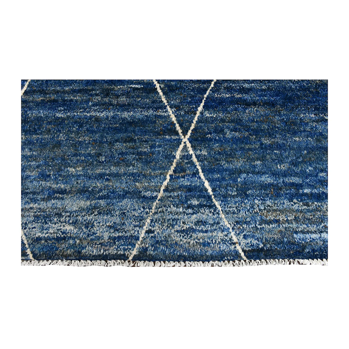 Fringe-end detail of Moroccan rug with ivory linework over layered blue and warm beige wool tones