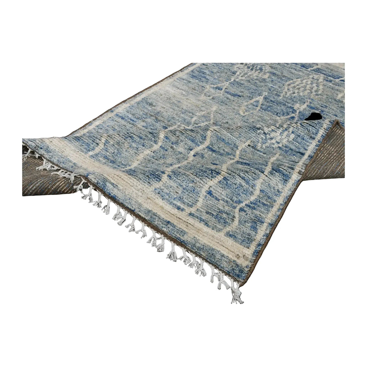 Folded-corner view of the blue Moroccan wool rug showing the pile, ivory fringe and reverse weave