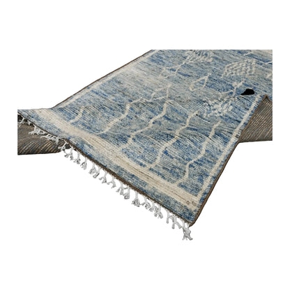 Folded-corner view of the blue Moroccan wool rug showing the pile, ivory fringe and reverse weave