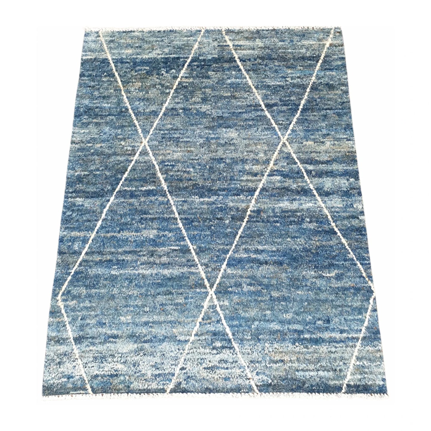 Angled view of blue Moroccan wool rug with open ivory diamond pattern, 180 x 140 cm