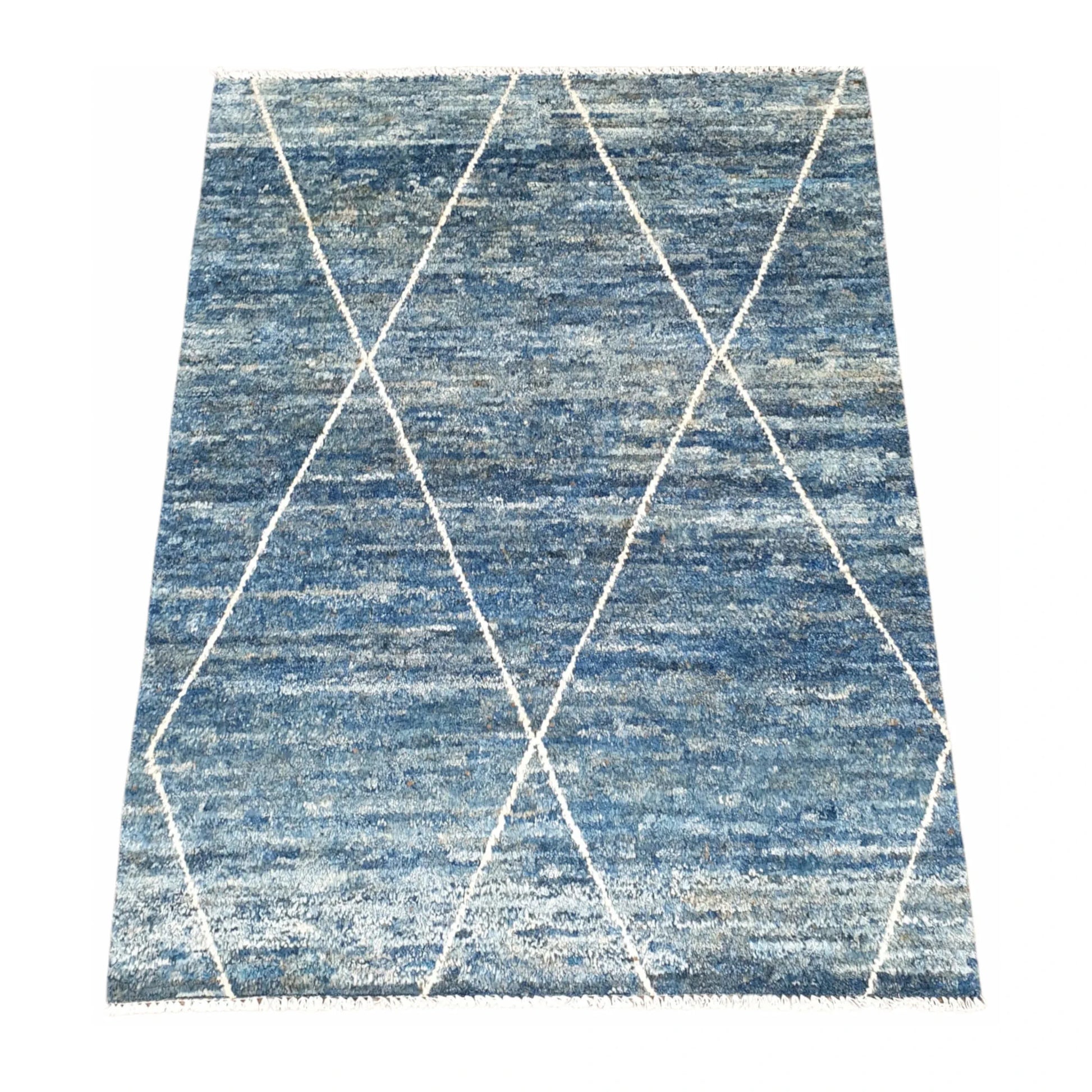 Angled view of blue Moroccan wool rug with open ivory diamond pattern, 180 x 140 cm