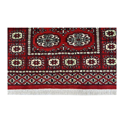 End field, border and fringe detail of Bokhara hand-knotted wool rug showing red pile, oval motifs and patterned border