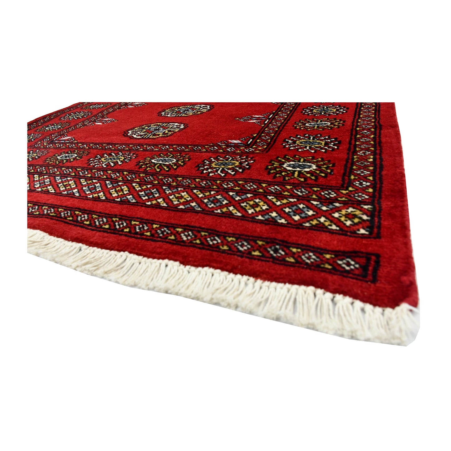 Angled corner and fringe view of Bokhara wool rug showing red field, geometric border and ivory fringe
