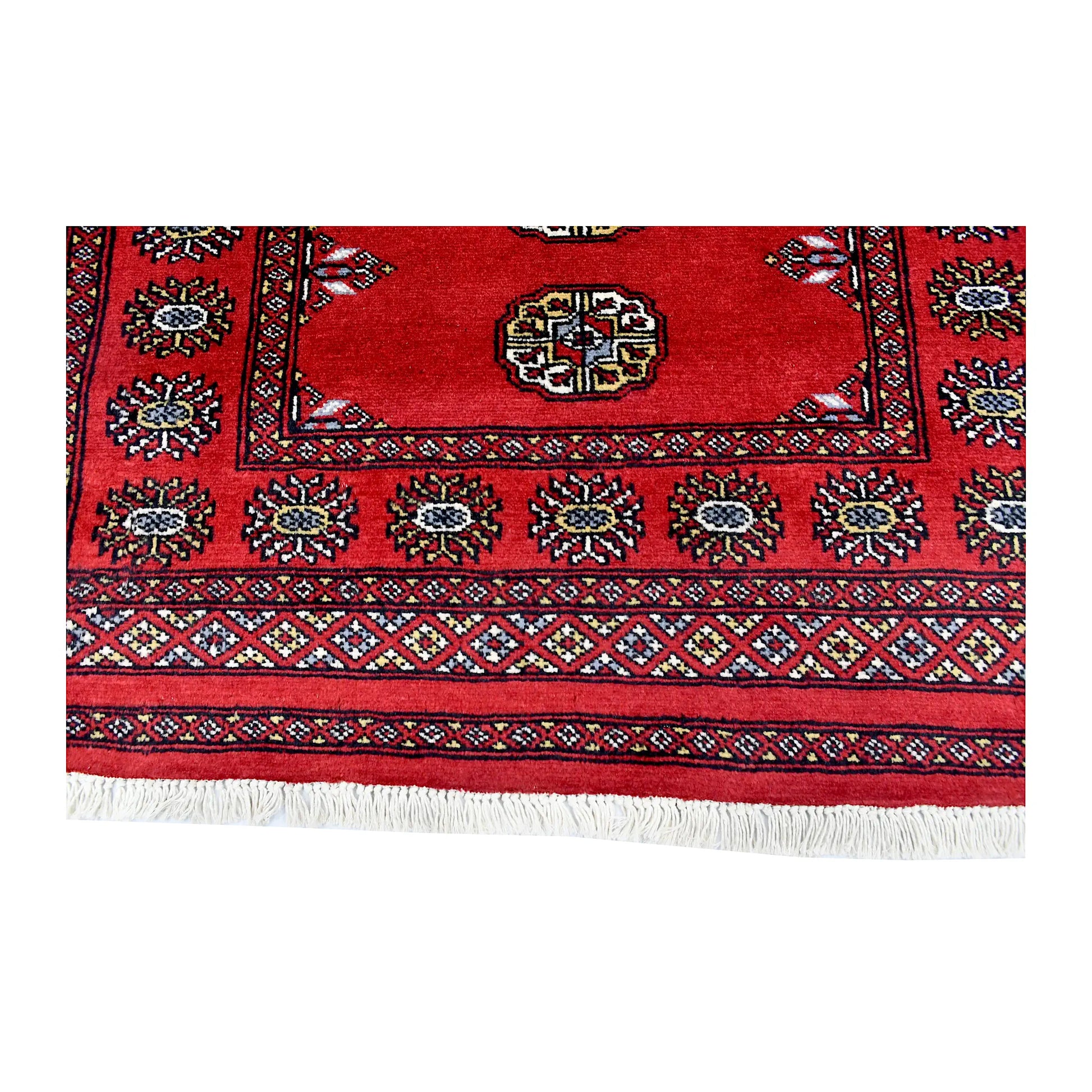 Field and border detail of Bokhara hand-knotted wool rug showing oval motifs, red pile and decorative border
