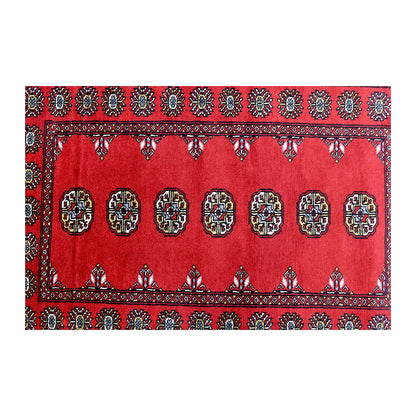 Length field detail of Bokhara wool rug showing repeated oval gul-style motifs with black and ivory accents