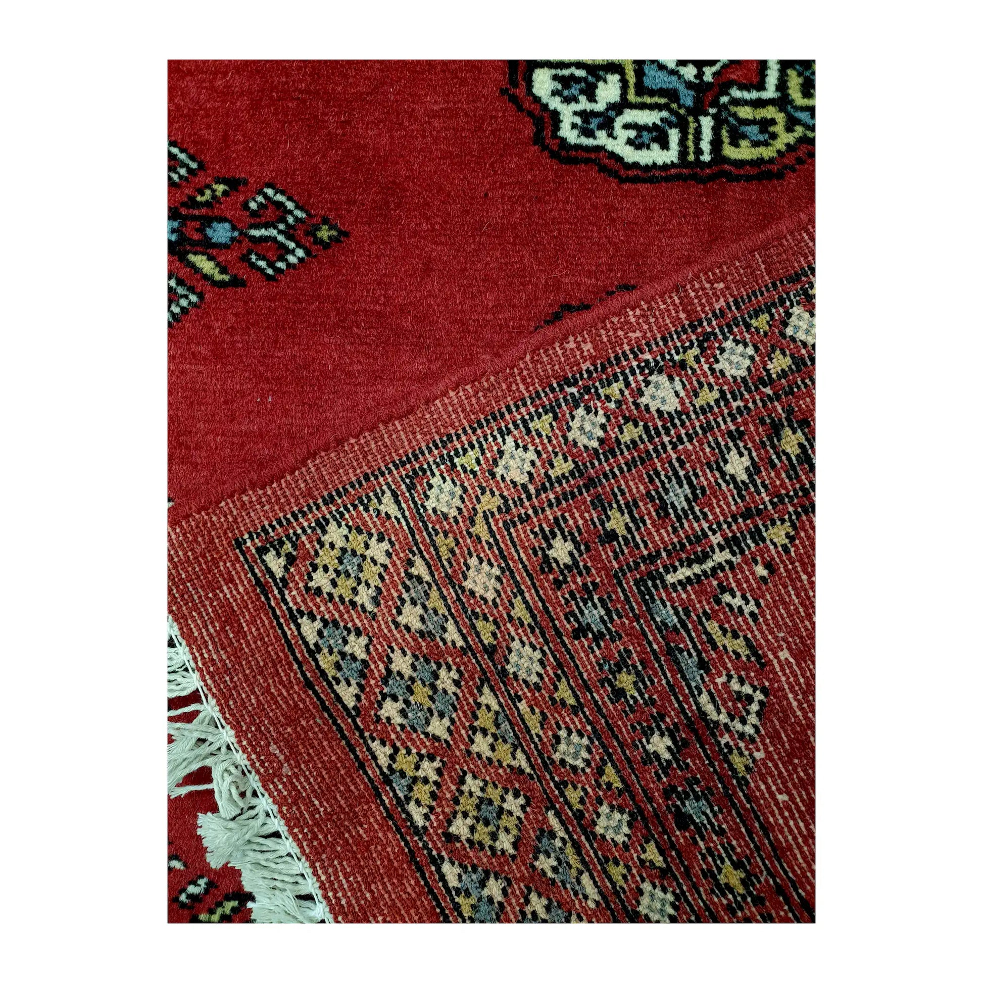 Folded corner reverse-weave detail of Bokhara hand-knotted wool rug showing back structure, border pattern and weave