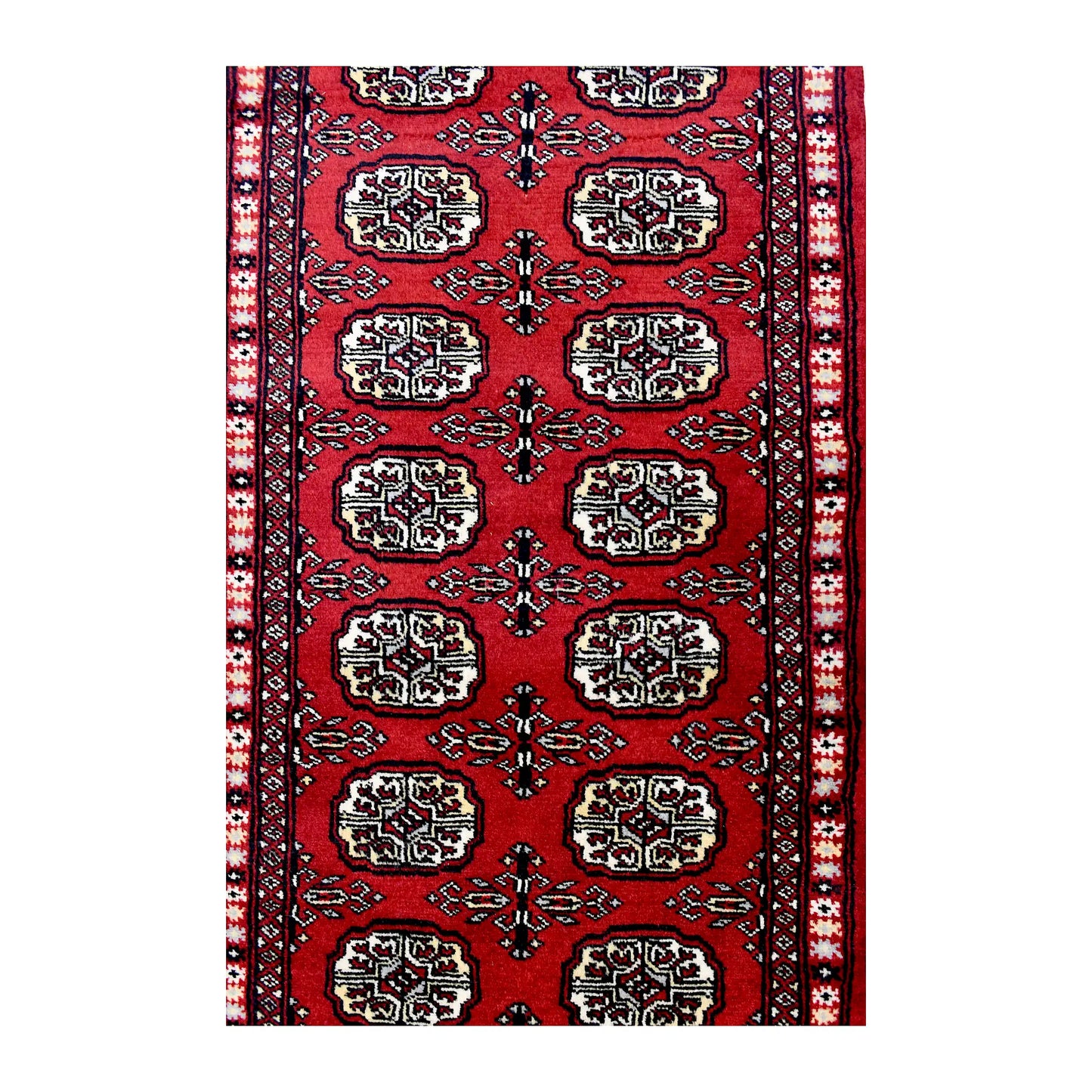 Length field detail of Bokhara wool runner rug showing repeated oval gul-style motifs and geometric border