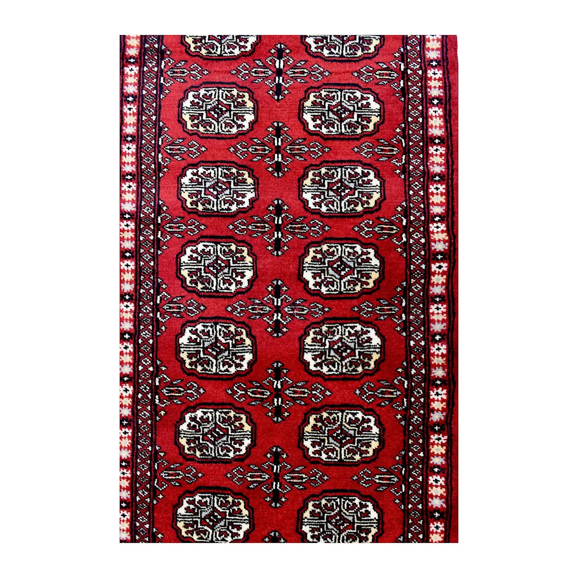 Length field detail of Bokhara wool runner rug showing repeated oval gul-style motifs and geometric border