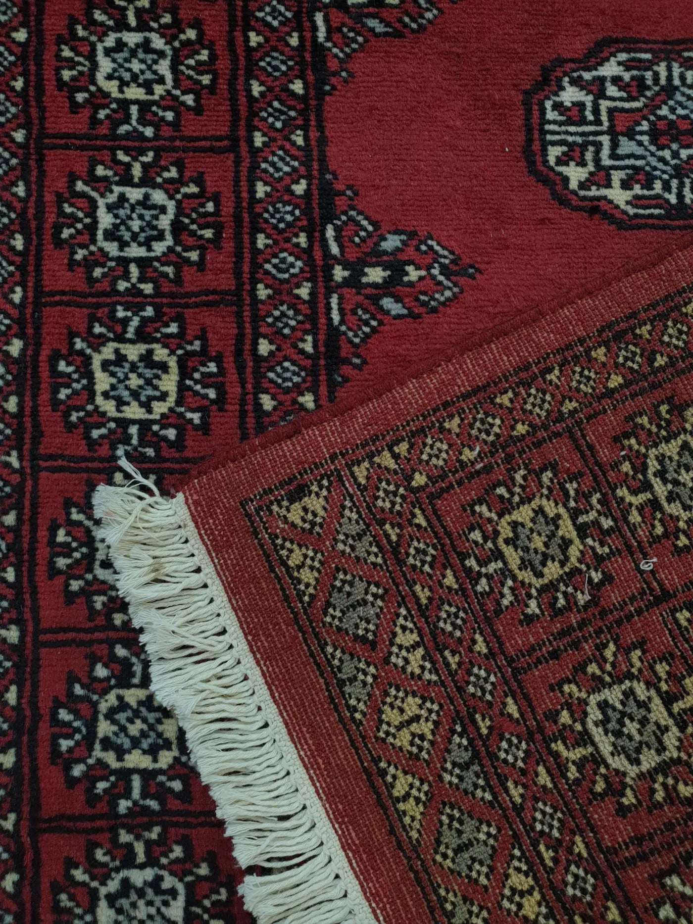 Bokhara hand-knotted wool runner rug 249 x 77 cm folded corner showing back detail