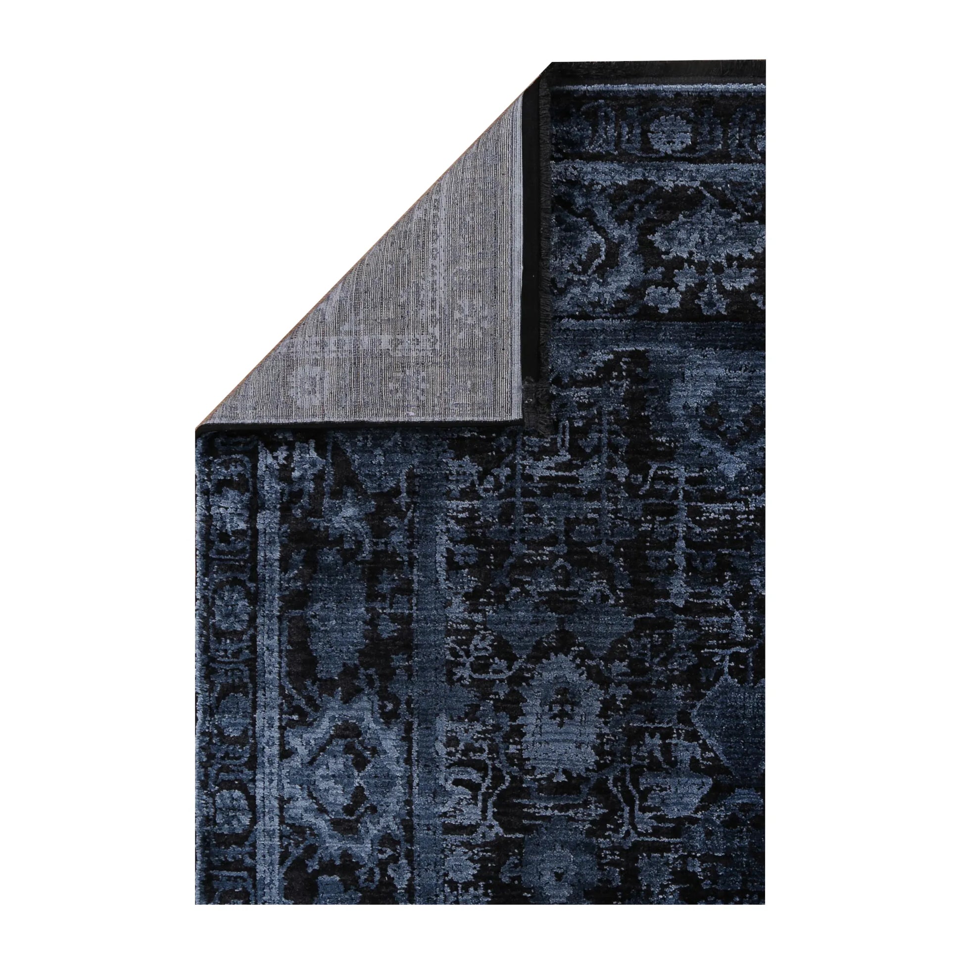 Folded corner detail of Brooklyn 300 navy blue ornate rug showing backing and edge texture