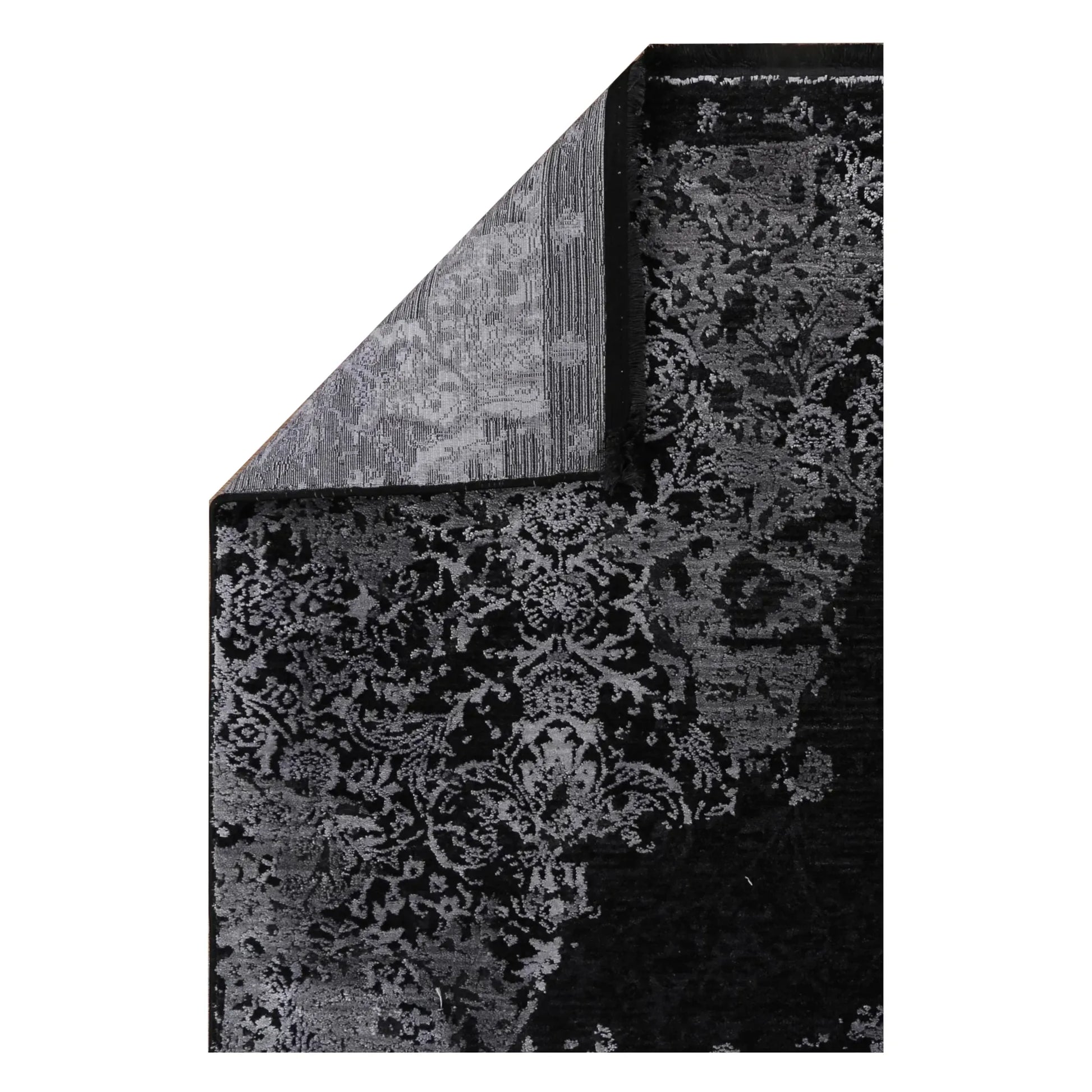 Folded corner of the Brooklyn 400 silver rug showing the ornamental pile, bound edge and woven backing
