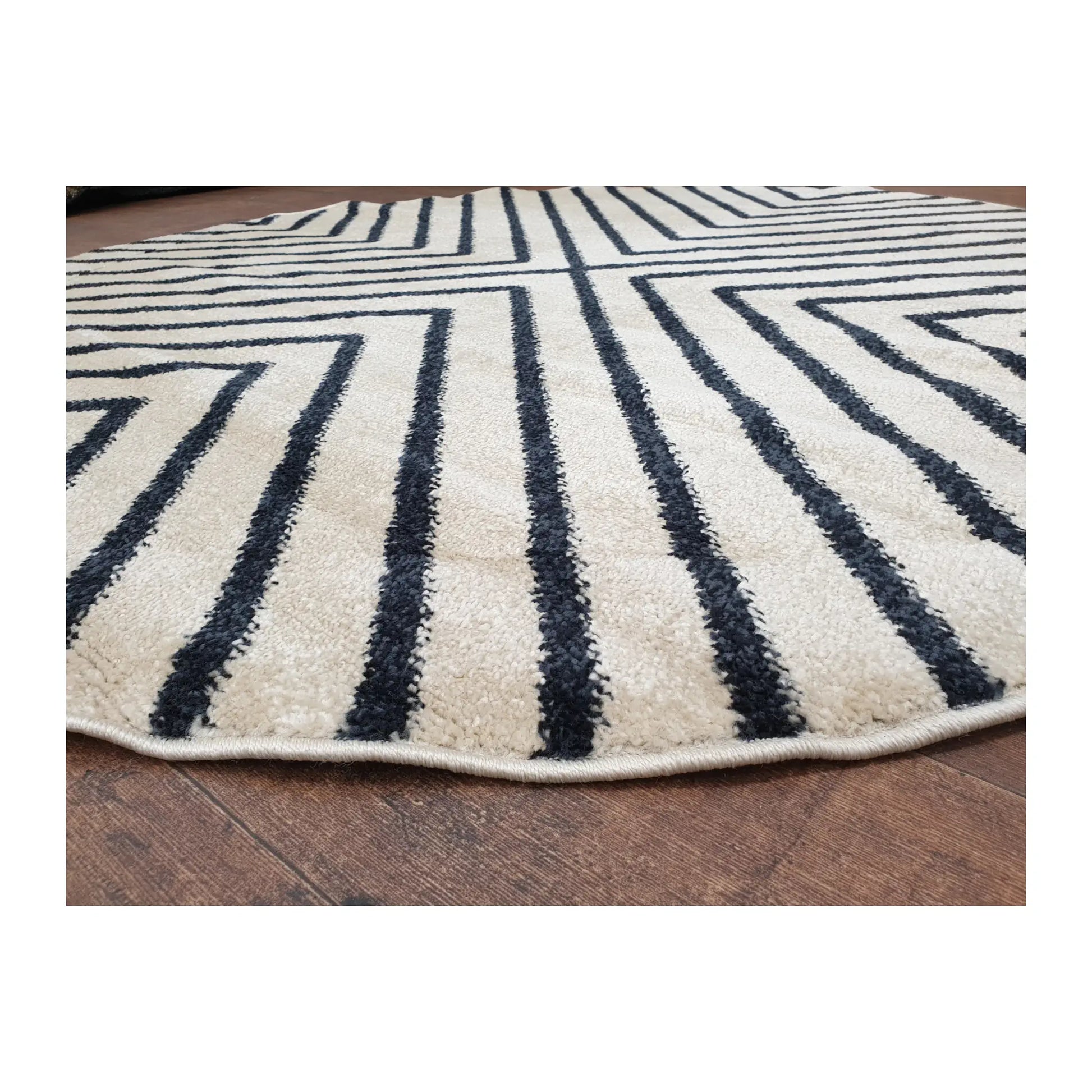 Low-angle close-up of charcoal round rug showing surface texture and diamond line design, 160 cm