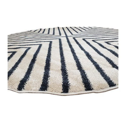Low-angle close-up of Primo round rug showing textured pile, rounded bound edge and charcoal linear pattern