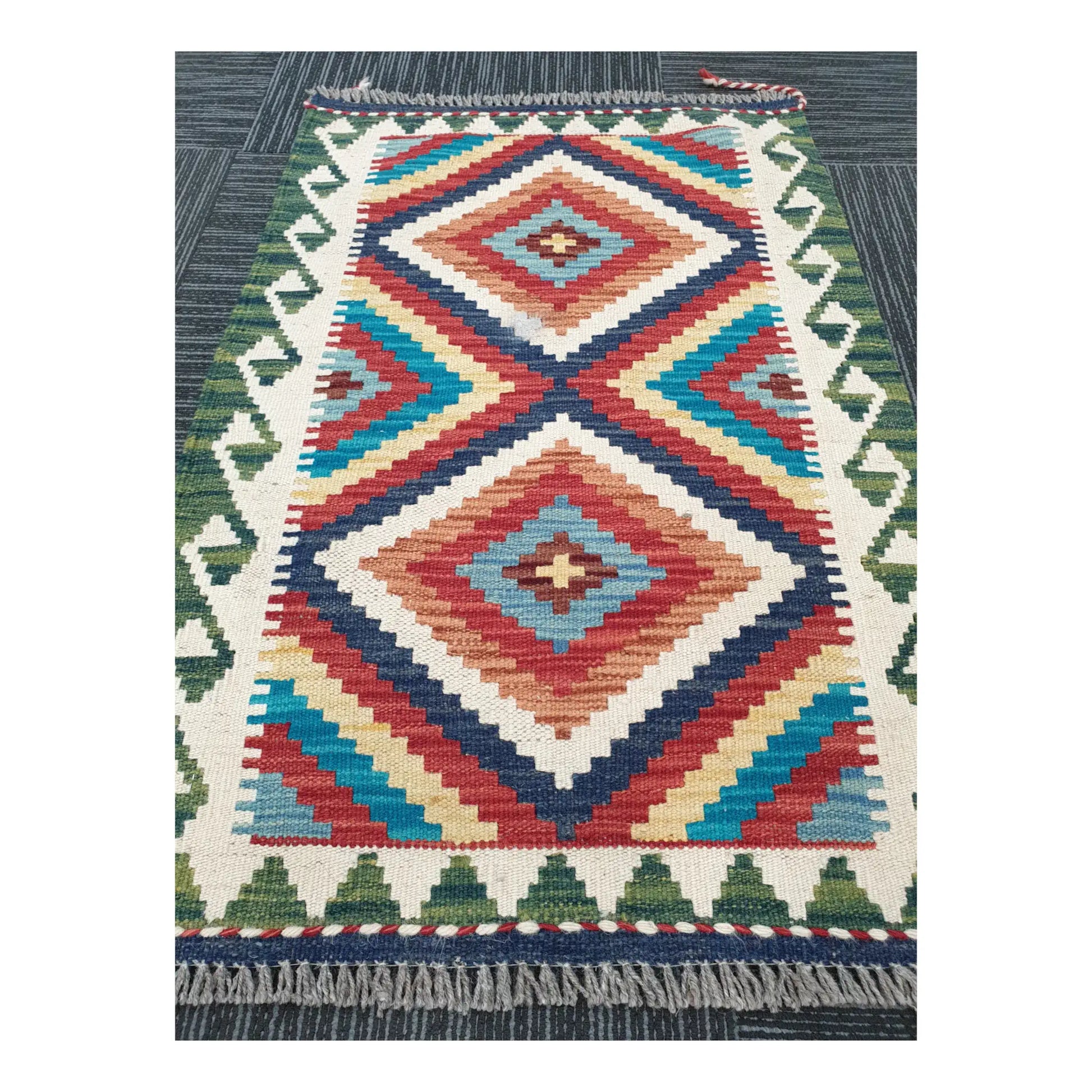 Angled view of Chobi Kilim flatweave rug showing bold geometric diamond design, 92 x 62 cm