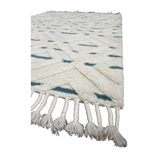 Angled view of cream and blue hand-tufted wool rug showing its sculpted pile, blue accents and long tassel fringe
